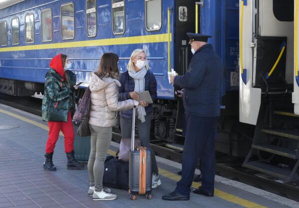 A train conductor checks the Covid Certificate of passengers, at a train station in Kyiv, Ukraine, Ukraine, Tuesday, Oct. 26, 2021. Coronavirus infections and deaths in Ukraine have surged to all-time highs amid a laggard pace of vaccination, which is one of the lowest in Europe. (AP Photo/Efrem Lukatsky)