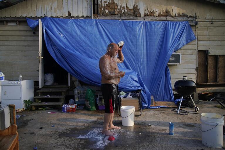 FILE - Starlin Billiot Sr. washes himself off beside a home where he has been living without power or running water in the aftermath of Hurricane Ida, Sept. 4, 2021, in Dulac, La. "I've been through four or five hurricanes and this was the worst," said Billiot about riding out the storm in the home. "I'm not gonna lie to you, I cried." (AP Photo/John Locher, File)