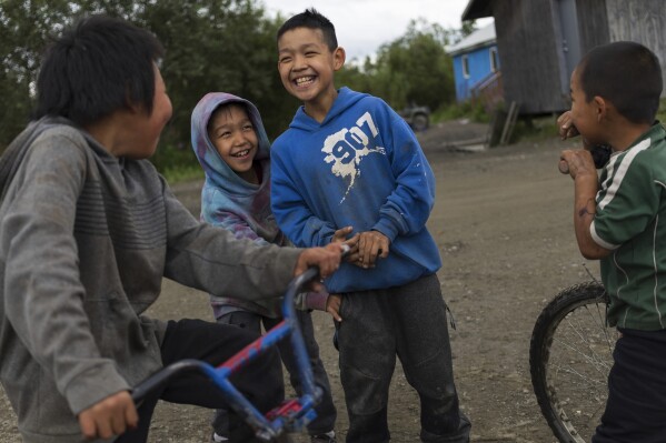 Joseph Phillip, 10 center, smiles with friends after lighting firecrackers, Saturday, Aug. 19, 2023, in Akiachak, Alaska. Small firecrackers are for sale without age restriction from the Akiachak Enterprises general store. (AP Photo/Tom Brenner)