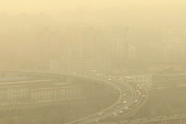 Cars drive along a highway shot through a glass window during a dust storm amid heavy pollution in Beijing, March 10, 2023. Almost the entire world breathes air that exceeds the World Health Organization's air-quality limits at least occasionally. (AP Photo/Borg Wong, File)