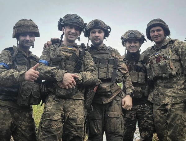 In this undated photo taken on the front-line, provided by Viktor Biliak, a Ukrainian infantryman with the 110th brigade, center, surrounded by fellow soldiers, poses for a photo, in Avdiivka, Donetsk region, Ukraine.  (Viktor Biliak via AP)