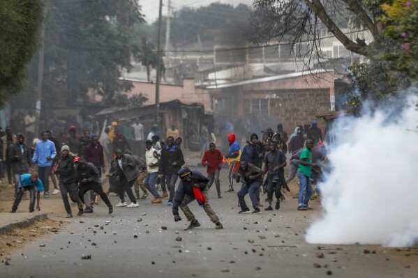 Protesters throw rocks at police during clashes next to a cloud of teargas in the Kibera area of Nairobi, Kenya Wednesday, July 19, 2023. Kenyans were back protesting on the streets of the capital Wednesday against newly imposed taxes and the increased cost of living. (AP Photo/Brian Inganga)