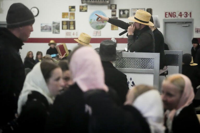 An auctioneer takes bids for books during the 56th annual mud sale to benefit the local fire department in Gordonville, Pa., Saturday, March 9, 2024. (AP Photo/Matt Rourke)