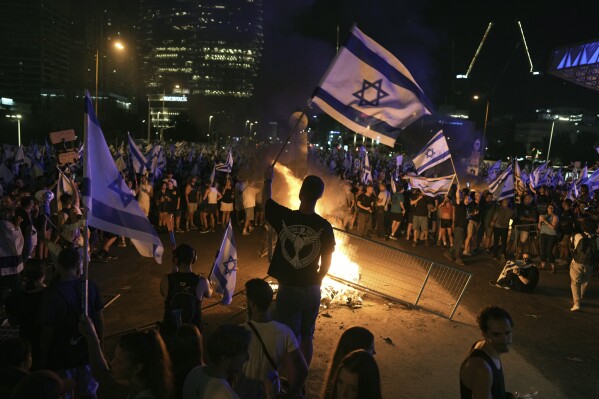 Demonstrators protest against plans by Prime Minister Benjamin Netanyahu's government to overhaul the judicial system, in Tel Aviv, Monday, July 24, 2023. Israeli lawmakers on Monday approved a key portion of Prime Minister Benjamin Netanyahu's divisive plan to reshape the country's justice system despite massive protests that have exposed unprecedented fissures in Israeli society. (AP Photo/Oded Balilty)