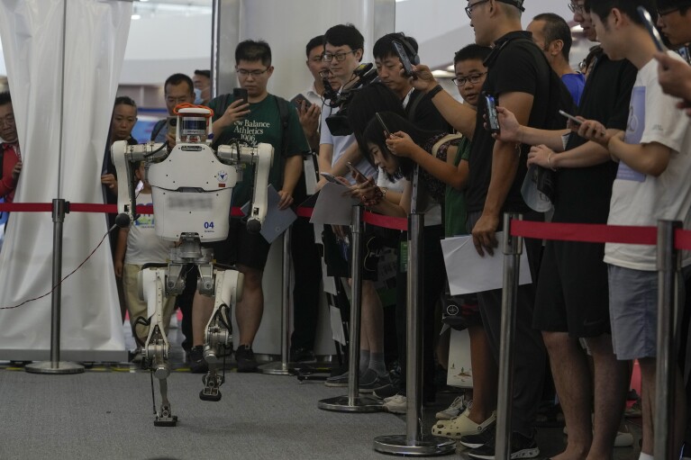 Visitors look at a remote control robot perform a walk during the annual World Robot Conference at the Etrong International Exhibition and Convention Center on the outskirts of Beijing, Thursday, Aug. 17, 2023. (AP Photo/Andy Wong)
