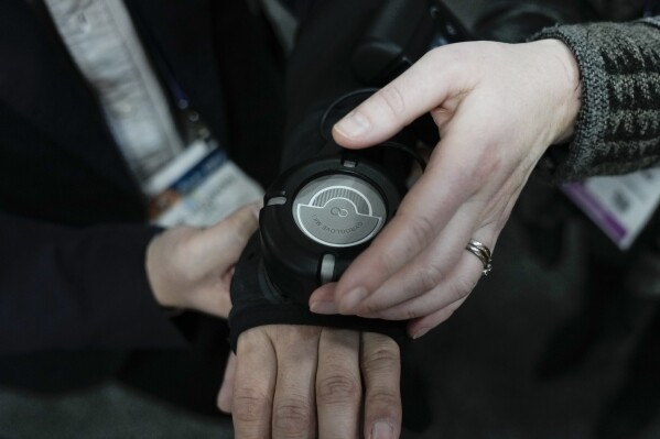 An attendee tests out the GyroGear, a wearable glove that is intended to help stabilize the hands of those with tremors, during the CES tech show Wednesday, Jan. 10, 2024, in Las Vegas. (AP Photo/Ryan Sun)