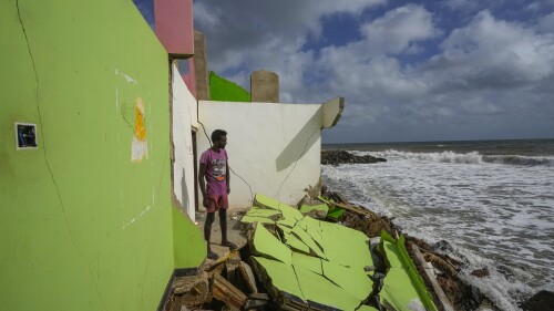Dilrukshan Kumara looks at the ocean as he stands by the remains of his family's home in Iranawila, Sri Lanka, Thursday, June 15, 2023. Much like the hundreds of other fishing hamlets that dot the coastline, the village of Iranawila suffers from coastal erosion. (AP Photo/Eranga Jayawardena)