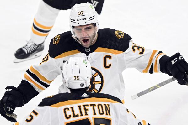 Boston Bruins' Patrice Bergeron (37) celebrates with teammate Connor Clifton after scoring against the Montreal Canadiens during the third period of an NHL hockey game in Montreal, Tuesday, Jan. 24, 2023. (Graham Hughes/The Canadian Press via AP)