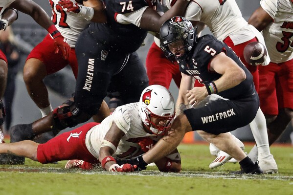 Louisville's Cam'Ron Kelly forces North Carolina State quarterback Brennan Armstrong (5) to fumble the ball during the second half of an NCAA college football game in Raleigh, N.C., Friday, Sept. 29, 2023. (AP Photo/Karl B DeBlaker)