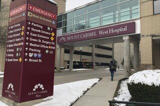 FILE - In this Jan. 15, 2019 file photo, the main entrance to Mount Carmel West Hospital is shown in Columbus, Ohio. The Ohio hospital system where an intensive-care doctor is accused of ordering painkiller overdoses for dozens of patients says it has put more employees on leave and changed key leaders at the hospital where nearly all those deaths occurred. Mount Carmel Health System said Wednesday, March 13 that 48 nurses and pharmacists under review have been reported to regulatory boards. It says 30 are on leave, and 18 no longer work there. The doctor was fired in December. (AP Photo/Andrew Welsh Huggins, File)