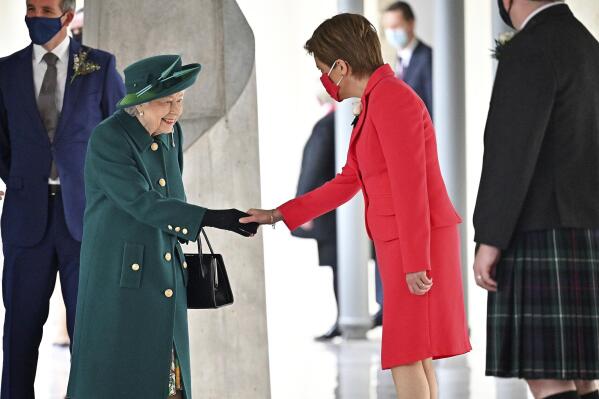 Britain's Queen Elizabeth II is greeted by Scotland's First Minister Nicola Sturgeon, right, as she arrives at the Scottish Parliament to deliver a speech in the debating chamber to mark the official start of the sixth session of Parliament, in Edinburgh, Scotland, Saturday Oct. 2, 2021. (Jeff J Mitchell/PA via AP)