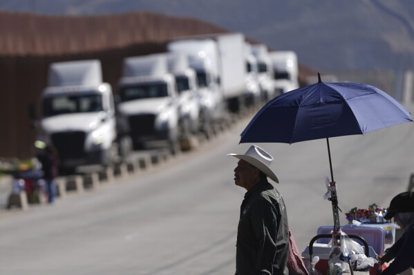2025年3月4日火曜日、メキシコのティフアナで、対メキシコ関税発効に伴い、国境を越えて米国に入ろうと並ぶトラック運転手にピーナッツを売るスサノ・コルドバ（右）。(AP Photo/Gregory Bull)