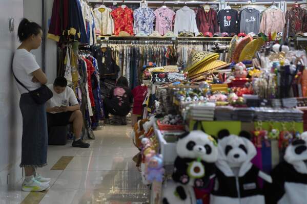 Vendors wait for customers at their store selling clothing and souvenirs inside a mall in Beijing on May 15, 2025. (AP Photo/Andy Wong)