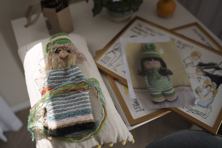 A doll that Tami Halevi, 86, is knitting lies on a table at the apartment where she is staying in Bat Yam, Israel, Feb. 9, 2024, after leaving her house in Kibbutz Nahal Oz. (AP Photo/Leo Correa)