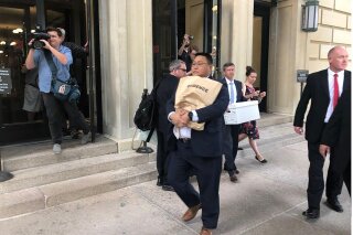 An unidentified man carries a box marked "evidence" as he leaves the Illinois State Capital in Springfield Ill., Tuesday, Sept. 24, 2019. An FBI spokesman says agents are at the Illinois state Capitol building in Springfield related to law enforcement work. The spokesman, John Althen, wouldn't provide details, saying Tuesday only that "FBI personnel are present at the state capitol engaged in authorized law enforcement activity." (AP Photo by John O'Connor)