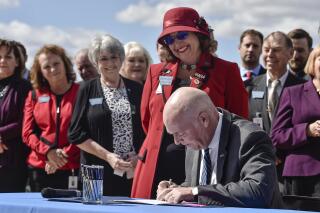 FILE - In this April 26, 2021, file photo, Republican Gov. Greg Gianforte signs a bill as bill sponsor Rep. Lola Sheldon-Galloway, R-Great Falls, looks on. Planned Parenthood of Montana has filed a lawsuit seeking to block four new laws restricting access to abortion in the state before they take effect. The laws are set to take effect Oct. 1. One would ban abortion after 20 weeks of gestations. Another would restrict access to medication abortion and ban access to medication abortion through telehealth. The lawsuit filed in Yellowstone District Court on Monday, Aug. 16, 2021 claims the laws violate Montana’s constitution. (Thom Bridge/Independent Record via AP, File)