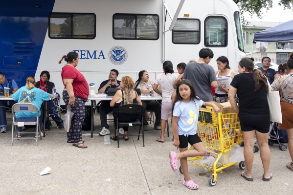 People affected by recent severe storms wait in line for assistance at a FEMA mobile unit Tuesday, May 21, 2024, at Spring Branch Family Development Center in Houston. (Yi-Chin Lee/Houston Chronicle via AP)