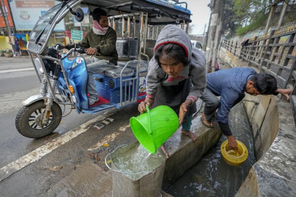 People collect water from an open drain on World Water Day in Guwahati, India, Friday, March 22, 2024. (AP Photo/Anupam Nath)