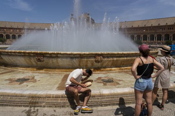 FILE - A man cools himself at a fountain in Seville, Spain, April 27, 2023. Record-breaking April temperatures in Spain, Portugal and northern Africa were made 100 times more likely by human-caused climate change, a new flash study found. (AP Photo/Santi Donaire, File)