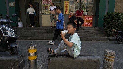 A child drinks from a bottle outside a lottery store in Beijing, Monday, July 17, 2023. China's economy grew at a 6.3% annual pace in the April-June quarter, much lower than analysts had forecast given the slow pace of growth the year before. (AP Photo/Ng Han Guan)