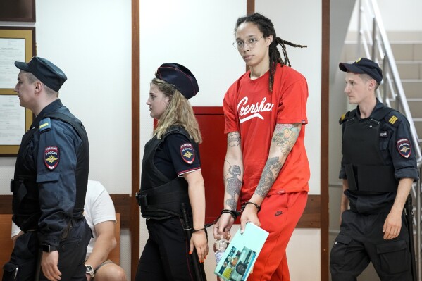 FILE - WNBA star and two-time Olympic gold medalist Brittney Griner is escorted to a courtroom for a hearing in Khimki outside Moscow, Russia, Thursday, July 7, 2022. Arrests of Americans in Russia have become increasingly common as relations between Moscow and Washington sink to Cold War lows. Some have been exchanged for Russians held in the U.S., while for others, the prospects of being released in a swap are less clear. (AP Photo/Alexander Zemlianichenko, File)