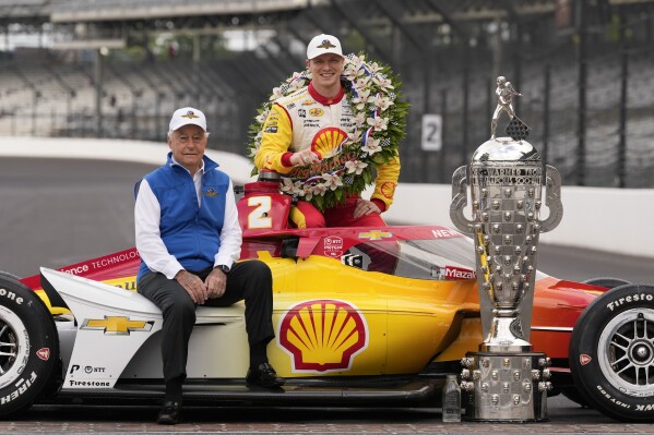 Roger Penske and Josef Newgarden pose with the Borg-Warner Trophy during the traditional winners photo session at Indianapolis Motor Speedway, Monday, May 27, 2024, in Indianapolis. Newgarden won the 108th running of the Indianapolis 500 auto race Sunday. (AP Photo/Darron Cummings)