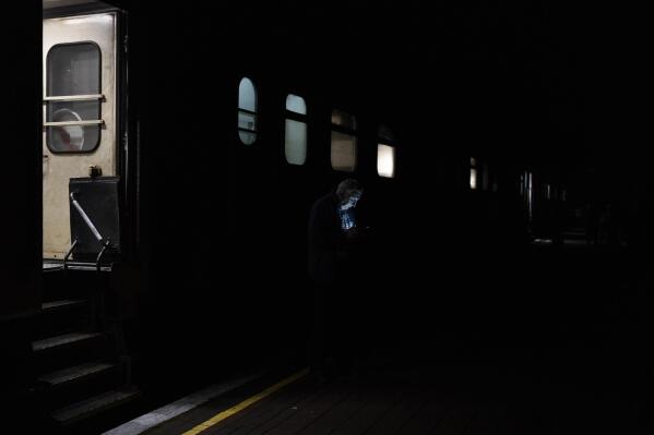 A man checks his phone before boarding the Kherson-Kyiv train at the Kherson railway station, southern Ukraine, Saturday, Nov. 26, 2022. Fleeing shelling, hundreds of civilians on Saturday streamed out of the southern Ukrainian city whose recapture they had celebrated just weeks earlier. (AP Photo/Bernat Armangue)