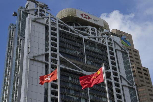 In this Wednesday, Sept. 8, 2021, photo, China mainland and Hong Kong flags are raised in front of the HSBC headquarters in Hong Kong. Banks in Hong Kong, Macao and China's Guangdong province can expect to launch investment products that are open to residents in these areas as soon as October, according to Hong Kong's monetary authority. (AP Photo/Kin Cheung)