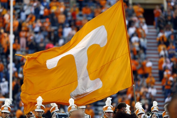 FILE - A Tennessee cheerleader runs with a flag before an NCAA college football game against Vanderbilt Saturday, Nov. 25, 2017, in Knoxville, Tenn. Tennessee has been in contact with NCAA investigators and a person with direct knowledge of the situation told The Associated Press on Tuesday, Jan. 30, 2024, the inquiry is into potential rules violations related to name, image and likeness compensation for multiple athletes.(AP Photo/Wade Payne, File)