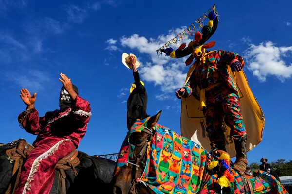 Enmascarados celebran el himno al Divino Espíritu Santo durante el Festival de las Cavalhadas en Pirenópolis, estado de Goiás, Brasil, el domingo 8 de junio de 2025. (Foto AP/Eraldo Peres)