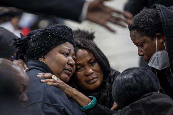 Patrick Lyoya's mother, Dorcas Lyoya, left, is embraced during the funeral for Patrick Lyoya at the Renaissance Church of God in Christ Family Life Center, Friday, April 22, 2022 in Grand Rapids, Mich. The Rev. Al Sharpton demanded that authorities publicly identify the Michigan officer who killed Patrick Lyoya, a Black man and native of Congo who was fatally shot in the back of the head after a struggle, saying at Lyoya's funeral Friday: “We want his name!" (Cory Morse/The Grand Rapids Press via AP)