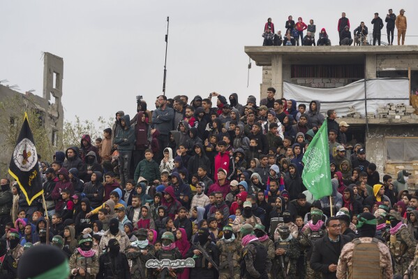 Palestinians gather as Hamas fighters deploy ahead of handing over four bodies to the Red Cross in Khan Younis, southern Gaza Strip, Thursday, Feb. 20, 2025. Israel has identified three of the bodies as hostages and said the other was of an unknown person. (AP Photo/Abdel Kareem Hana)