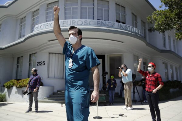 FILE - In this Tuesday, April 21, 2020 file photo, nurses Michael Gulick, center, and Angela Gatdula, right, hold their arms up in protest outside of Providence Saint John's Health Center in Santa Monica, Calif. The hospital suspended ten nurses, including Gulick, from their jobs the previous week after they refused to care for COVID-19 patients without being provided protective N95 face masks. Gatdula says she contracted COVID-19 and has recovered. (AP Photo/Marcio Jose Sanchez)