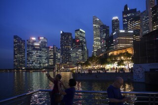 FILE - Tourists take a picture with the skyline of Singapore, on Nov. 6, 2023. Singaporean Transport Minister S. Iswaran was charged Thursday, Jan. 18, 2024, in the first ministerial corruption case ever seen in the Asian financial hub known for squeaky clean government. (AP Photo/Vincent Thian, File)