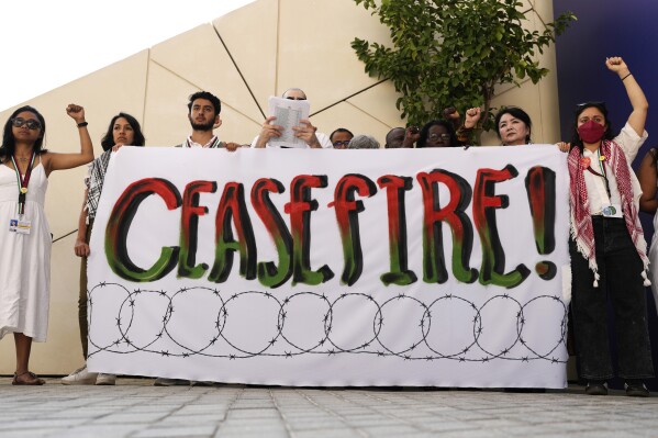 Demonstranten houden hun vuisten omhoog en een bord waarin wordt opgeroepen tot een staakt-het-vuren in de oorlog tussen Israël en Hamas op de COP28 VN-klimaattop, zondag 3 december 2023, in Dubai, Verenigde Arabische Emiraten.  (AP Foto/Rafiq Maqbool)