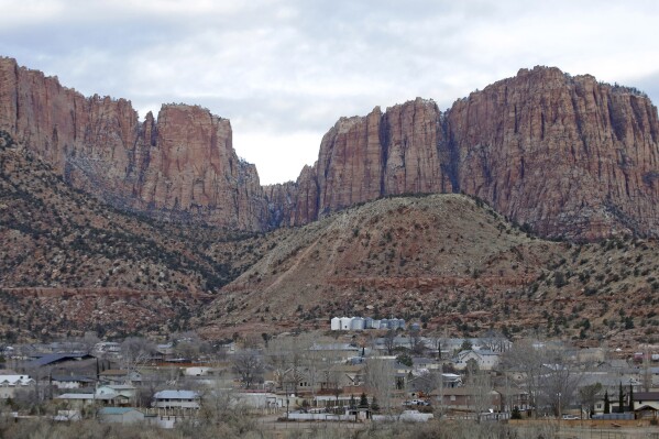 FILE - Hildale, Utah, is pictured sitting at the base of Red Rock Cliff mountains, with its sister city, Colorado City, Ariz., in the foreground on Dec. 16, 2014. On Tuesday, March 19, 2024, a businessman pleaded guilty to conspiring with the leader of an offshoot polygamous sect in the Colorado City-Hildale area to transport underage girls across state lines for sexual activity. The guilty plea by 53-year-old Moroni Johnson marked the first man to be convicted in what authorities say was a scheme to orchestrate sexual acts involving children. (AP Photo/Rick Bowmer, File)