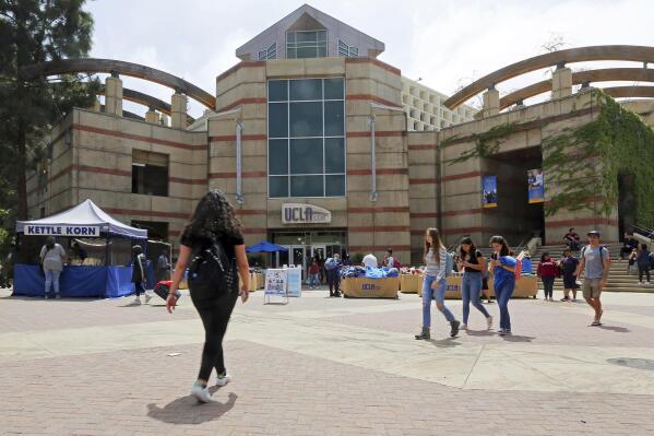 FILE - People pass Ackerman Student Union on the campus of the University of California, Los Angeles, April 26, 2019. The University of California, Los Angeles said Thursday, May 26, 2022, it was reinstating an indoor mask policy as coronavirus cases surge in the nation's most populous state, which now forecasts hospitalizations will triple in the next month. (AP Photo/Reed Saxon, File)
