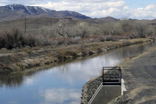FILE — Water is shown in an irrigation canal in Fernley, Nev. near Reno on March 18, 2021. A U.S. appeals court has breathed new life into a rural Nevada's town's unusual bid to halt government repairs to an aging, federal irrigation canal that burst and flooded nearly 600 homes 15 years ago. The town of Fernley, area farmers and ranchers in the high desert 30 miles (48 kilometers) east of Reno say the renovation that finally began this year might help guard against another failure of the 118-year-old earthen canal. (AP Photo/Scott Sonner, File)