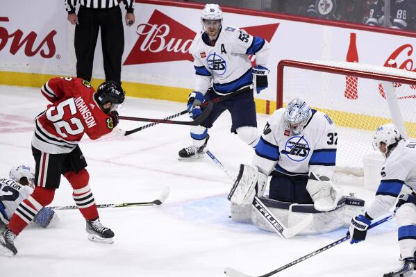 Winnipeg Jets goaltender Connor Hellebuyck (37) makes a save on a shot by Chicago Blackhawks' Reese Johnson (42) during the first period of an NHL hockey game in Winnipeg, Manitoba, Saturday, Nov. 5, 2022. (Fred Greenslade/The Canadian Press via AP)