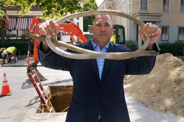 Providence Water general manager Ricky Caruolo, shows a length of lead residential water supply line, which was removed and replaced with copper, outside a home, Thursday, June 29, 2023, in Providence, R.I. He said officials have addressed lead head-on, improving water treatment, educating the public about lead and providing no-interest loans for pipe removal. (AP Photo/Charles Krupa)