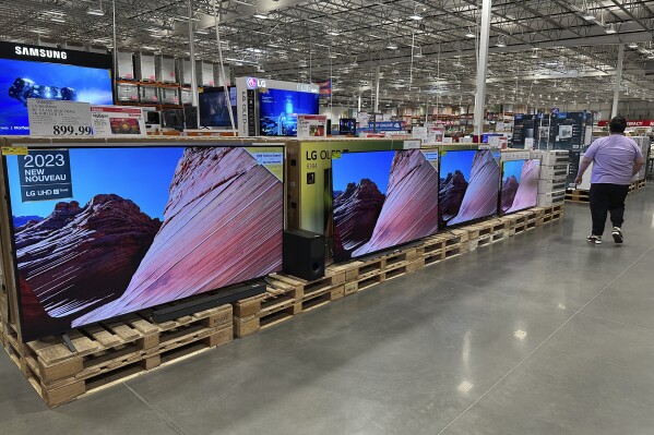 A shopper passes by a display of large-screen televisions in a Costco warehouse Monday, Feb. 3, 2025, in east Denver. (AP Photo/David Zalubowski)