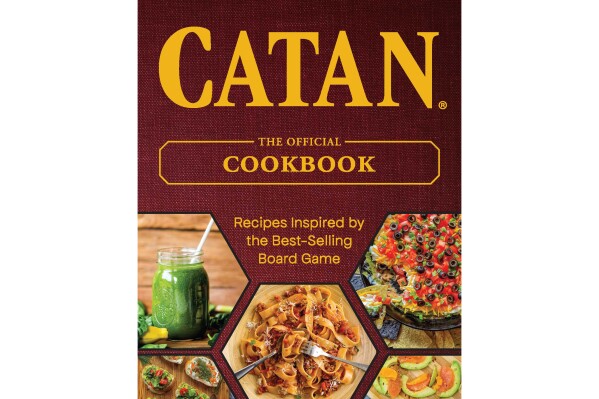This cover image released by Ulysses Press shows "Catan: The Official Cookbook." It includes 77 recipes inspired by the multiplayer game phenomenon, dishes like Forest Dweller’s Dip, Tavern Ale Pie and Fireside Banana Boats. (Ulysses Press via AP)