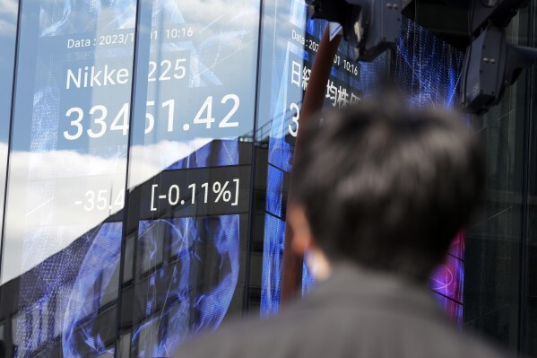 A person stands near an electronic stock board showing Japan's Nikkei 225 index at a securities firm Friday, Dec. 1, 2023, in Tokyo. Asian shares declined on Friday even after Wall Street closed out its best month of the year with big gains in November. (AP Photo/Eugene Hoshiko)