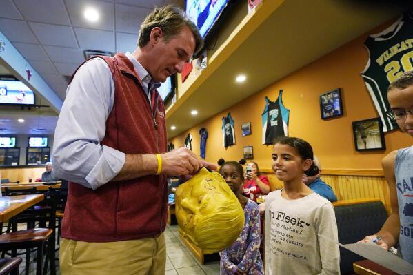 Virginia Republican gubernatorial candidate Glenn Youngkin signs a Donald Trump Halloween mask for a fan during a meet and greet at a sports bar in Chesapeake, Va., Monday, Oct. 11, 2021. Youngkin faces former Governor Terry McAuliffe in the November election. (AP Photo/Steve Helber)