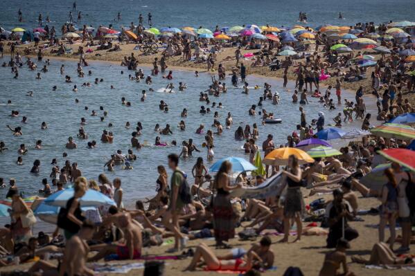 FILE - People cool off in the water on a hot and sunny day at the beach in Barcelona, Spain, July 15, 2022. Earth’s fever persisted last year, not quite spiking to a record high but still in the top five or six warmest on record, government agencies reported Thursday, Jan. 12, 2023. (AP Photo/Emilio Morenatti, File)