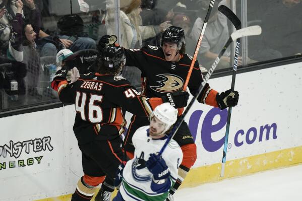 Anaheim Ducks' Sonny Milano, upper right, celebrates his goal with Trevor Zegras (46) as Vancouver Canucks' Conor Garland, foreground, skates past them during the second period of an NHL hockey game Sunday, Nov. 14, 2021, in Anaheim, Calif. (AP Photo/Jae C. Hong)