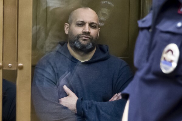 FILE - Sergei Khadzhikurbanov, accused of the murder of journalist Anna Politkovskaya, awaits the judge's verdict in a glass cage, at the Moscow City Court, Russia, Wednesday, May 21, 2014. A lawyer for Khadzhikurbanov said Tuesday, Nov. 14, 2023, that he received a presidential pardon after doing a stint fighting in Ukraine. (AP Photo/Pavel Golovkin, File)