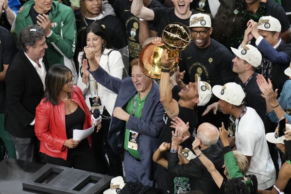 Boston Celtics head coach JJoe Mazzulla, center right, raises the trophy beside owner Stephen Pagliuca, center left, after defeating the Dallas Mavericks in Game 5 of the NBA basketball finals, Monday, June 17, 2024, in Boston. (AP Photo/Michael Dwyer)