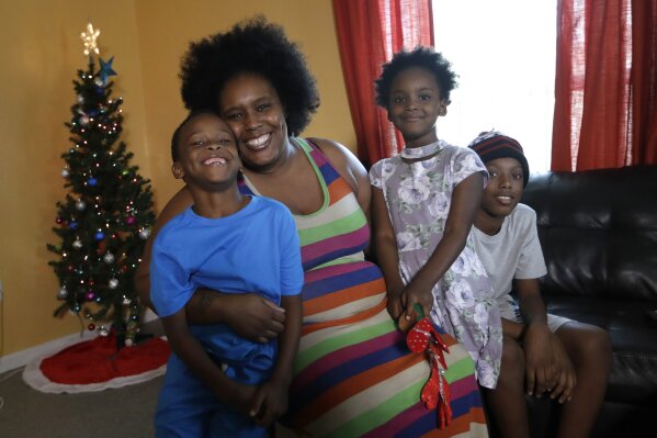 
              Keiondra Ross poses with her children Kaydan Lawson, left, Kayla Lawson, and Daniel Lawson, right, at their home, Wednesday, Dec. 19, 2018, in Miami. Ross is a single mother and receives donations from charities to help put presents under her Christmas tree. The recent closure of Toys R Us created some collateral damage -- the Toys for Tots charity drive. More than 250,000 toys donated by consumers and $5 million, 40 percent of corporate giving, came through Toy R Us last year, holes the annual Marine Corps' community effort is working to fill. (AP Photo/Lynne Sladky)
            