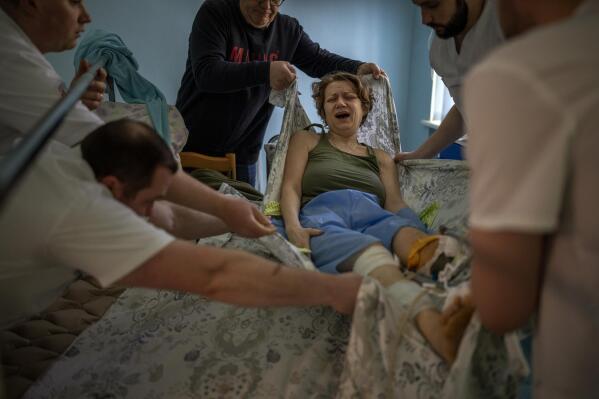 Olena Viter, 45, is transferred to a stretcher before being taken to the operating theatre to undergo further surgery, at a public hospital in Kyiv, Ukraine, Tuesday, May 10, 2022. The explosion that took Olena Viter's left leg also took her son, 14-year-old Ivan, a budding musician already playing in a small orchestra. Her husband Volodymyr buried him and another boy killed in the same blast under a guelder-rose bush in their garden. (AP Photo/Emilio Morenatti)